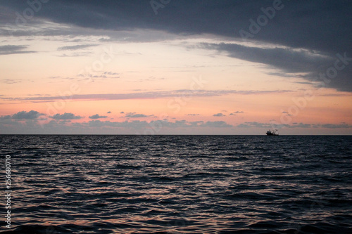 Golden  Fiery sunset on the Black Sea  on the beach. Coast  stones  waves  sun  beautiful sky  clouds. August  Batumi  Georgia. Boat  ship. Water  lightness  play. Pink  lilac  crimson