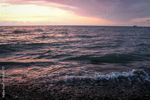 Golden  Fiery sunset on the Black Sea  on the beach. Coast  stones  waves  sun  beautiful sky  clouds. August  Batumi  Georgia. Water  lightness  play. Pink  lilac  crimson