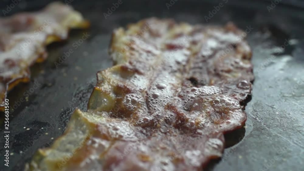 Close-up of a slice of bacon fried on a hot grill slow motion Close-up of a slice of bacon fried on a hot grill slow motion