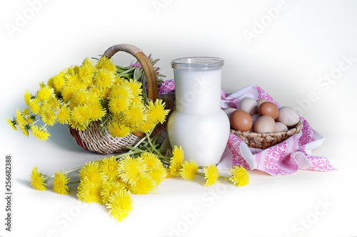 Still life with yellow dandelions in a vase and a jug of milk on a white kitchen background