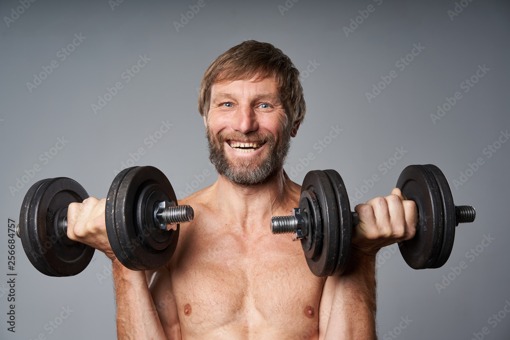 mature man shirtless standing with dumbbells smiling