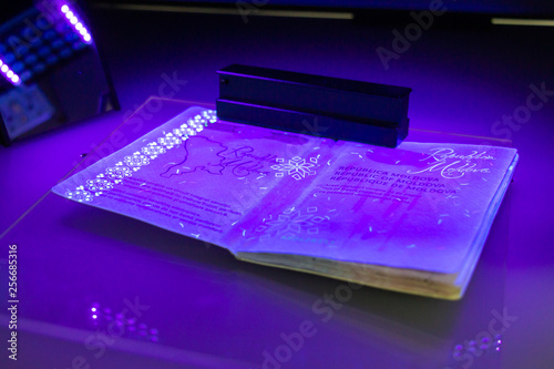 Process of the Moldovan passport checking, close-up. The study of protective elements of the document in ultraviolet light. High security printing for passport. Passport protection against fraud