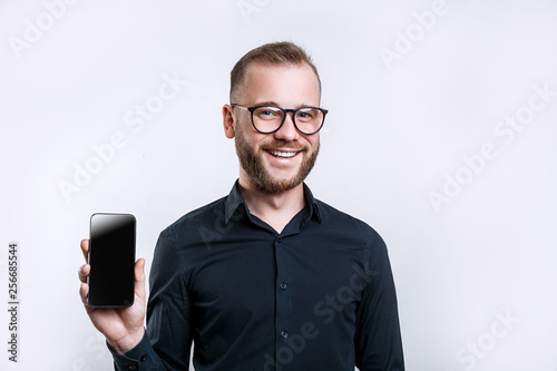 Portrait of happy man in glasses demonstrating blank smartphone with smile. Copyspace for yor app photo