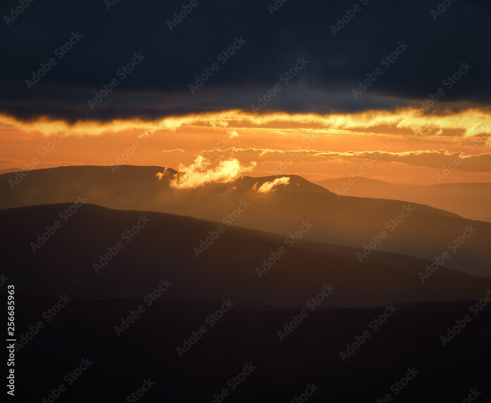 A small wisp of golden cloud emerges from the great dark cloud