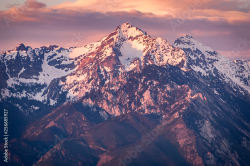 Sunset in the mountains gives the rocky crags a glow of purple.