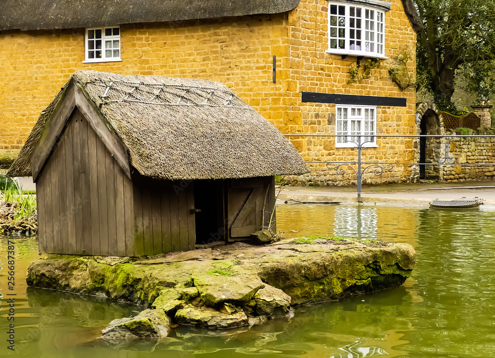 Old wooden and thatched Duck pond house, on weathered stone island in  public village pond. Background of local stone cottage. Wroxton,  Oxfordshire. England. Stock Photo | Adobe Stock