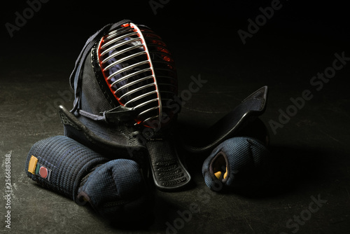 Kendo gloves and traditional helmet on dark surface