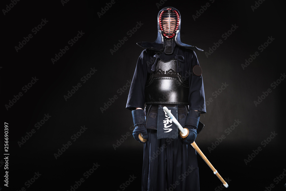 Naklejka premium Kendo fighter in armor holding bamboo sword on black