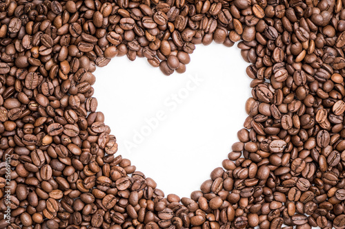 Shape of white heart in the middle of freshly roasted coffee beans texture.Copy space.