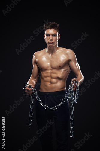 Teenager men sportsmen. Portrait of a brutal boy with chains. Athlete bodybuilder on black background.