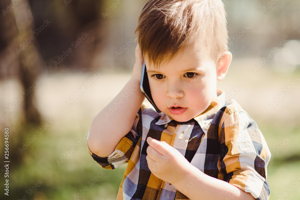 little baby is talking on the phone in the street