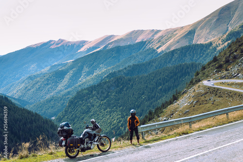 Woman with adventure motorcycle. Motorbike rider. Top of mountain road. Motorcyclists vacation. Travel and active lifestyle Transfagarasan Romaia, copy space