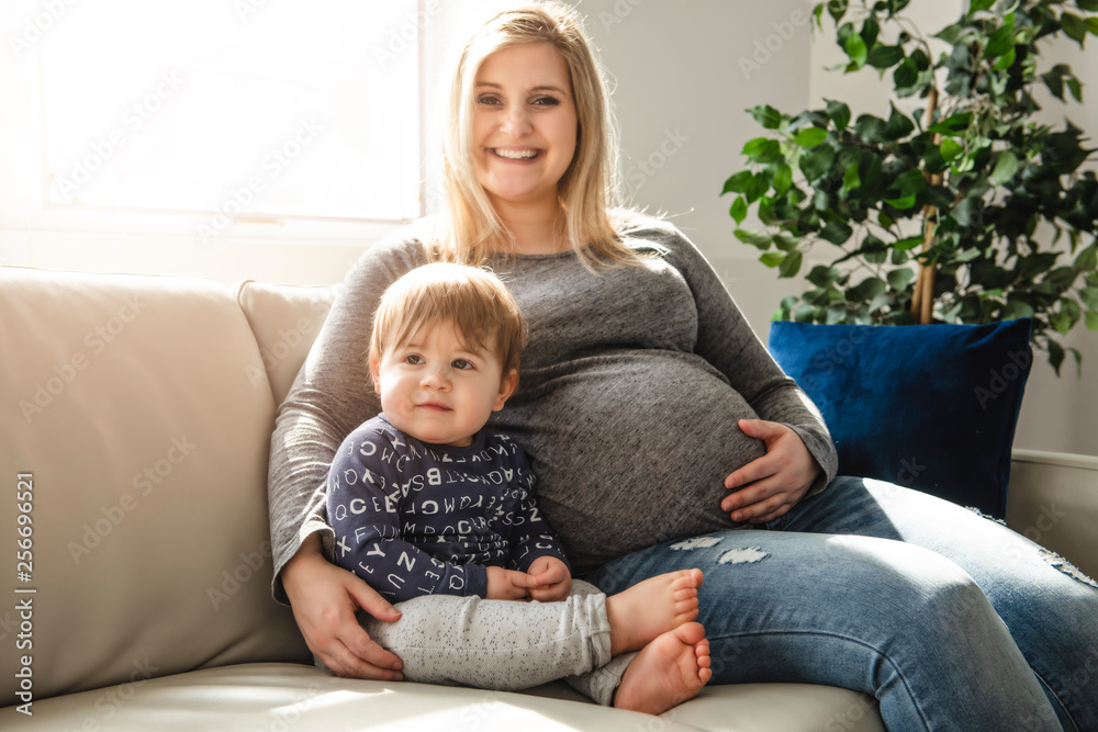 A happy pregnant mother and little son at home