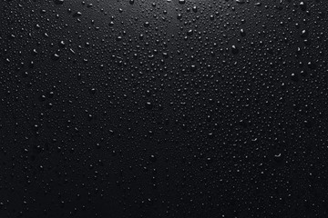 Shiny water drops on black surface, background