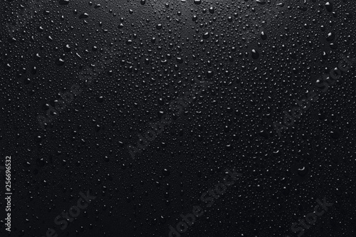 Shiny water drops on black surface, background photo