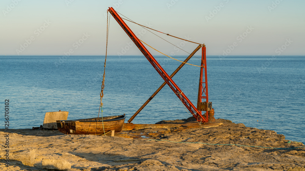 A fishing boat and a crane near Portland Bill Lighthouse, Jurassic Coast, Dorset, UK