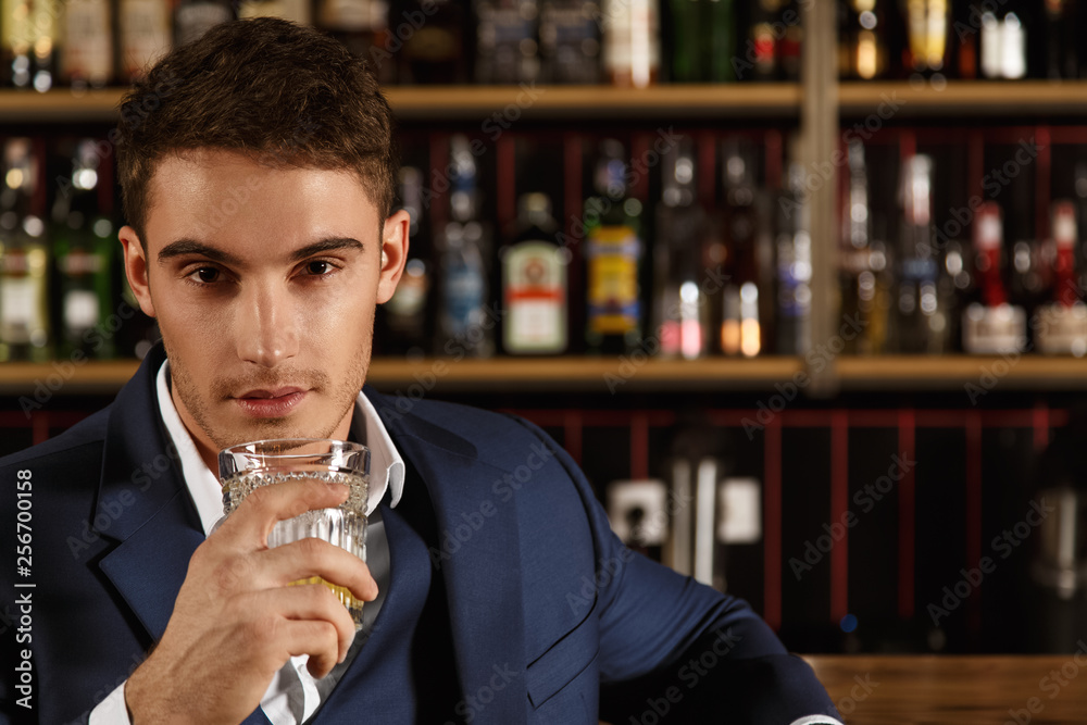Share a drink with me. Closeup portrait of a handsome guy holding a whiskey glass looking at the camera seductively copyspace Share a drink with me. Closeup portrait of a handsome guy holding a whiskey glass looking at the camera seductively copyspace