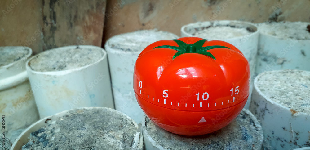 Pomodoro timer on white PVC pipes stacked on floor with concrete.