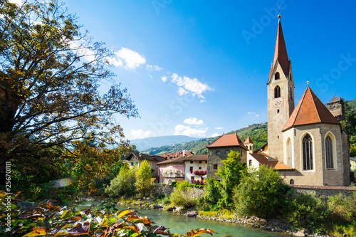 church and colorful houses along river Isarco, Chiusa, Italy photo