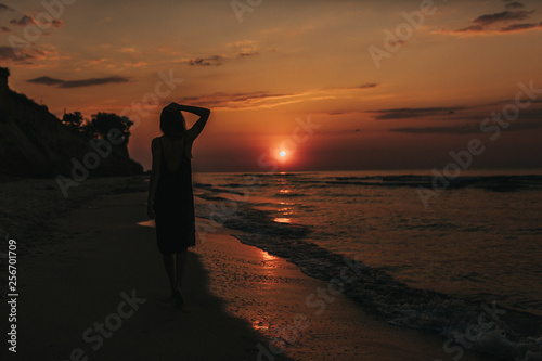 morning sunrise The girl goes on the beach in the morning. girl silhouette at sunset. woman relaxes by the sea. © Andriy Medvediuk
