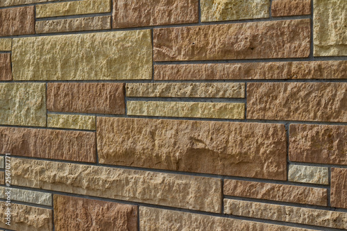 Attractive kasota limestone brick wall background with bricks in varying shades of brown (angle view)