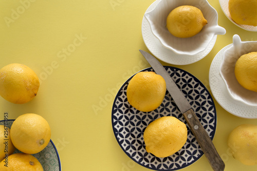 Fresh raw lemons and porcelain  tablewares on fresh yellow background. Still life, background, fresh food design photo