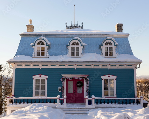 Beautiful two-chimneyed Second Empire turquoise house with metal sheet mansard roof and dormer windows seen in winter in old Lévis, Quebec, Canada photo