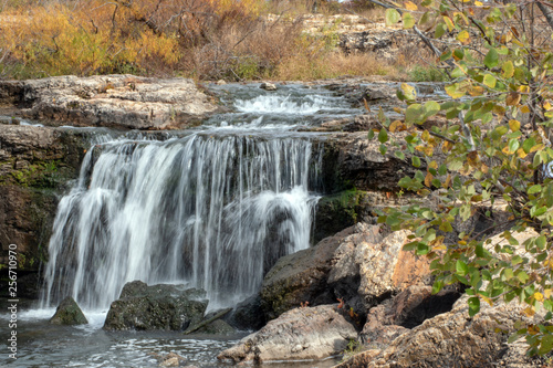 Water flows smooth and gracefully over the rocks at The Falls in Joplin, MO on an autumn day.