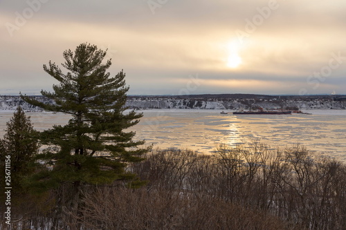 Horizontal bird   s eye view from the Plains of Abraham of the partly frozen St. Lawrence river in winter with merchant boat moored on its south shore  Quebec City  Quebec  Canada