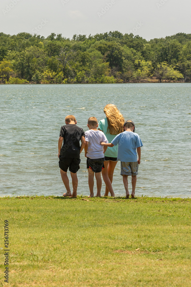 Obraz premium curious children standing next to the water at a lake