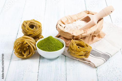 uncooked taglatelle pasta and ingredients: grounded spinach powder and whole wheat flour photo