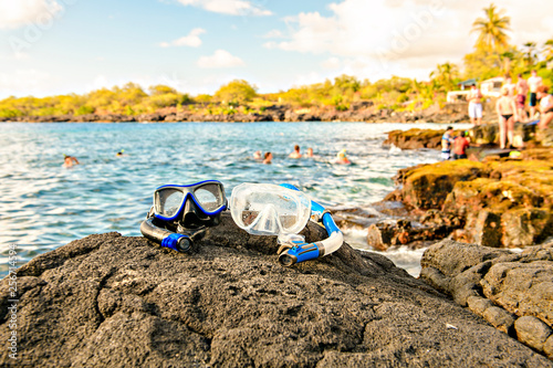 A Colorful snorkle or diving mask located on the rocks with snorkling group on the back