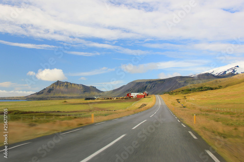 Road with farm and mountains in background (Iceland)