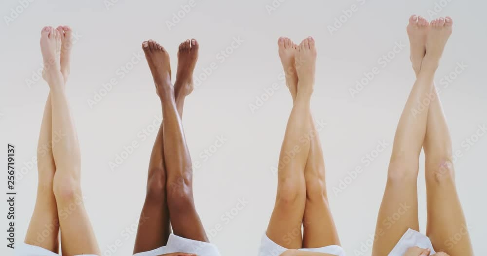 Slow motion of beautiful young women of different ethnicities with perfect firm and slim bodies crossing hairless soft and silky legs isolated on a white background. 