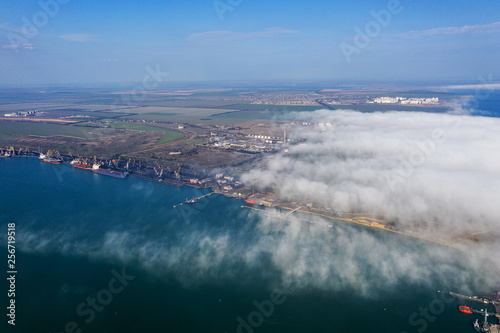 Aerial view of panoramic seaport warehouse and container ship  crane vessel working for delivery of delivery containers. Yuzhny Sea Industrial Port  Port Plant  Ukraine  2019. Ships in sea port  fog