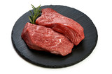 Fresh raw beef steaks with rosemary on slate shale plate, sliced meat, close-up, isolated on white background