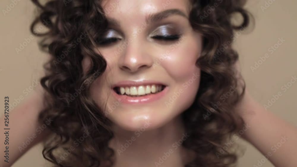 Beautiful brunette girl with a perfectly curly hair, and classic make-up posing in the studio. Beauty face. Beautiful brunette girl with a perfectly curly hair, and classic make-up posing in the studio. Beauty face.