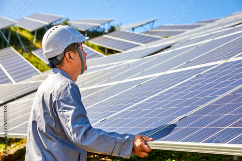 Asian engineer patrolling the solar photovoltaic district on the top of the mountain