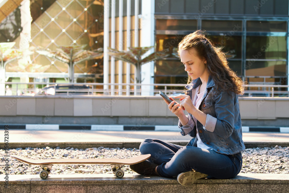 teen girl having a mobile phone sit on a floor in a city teen girl having a mobile phone sit on a floor in a city