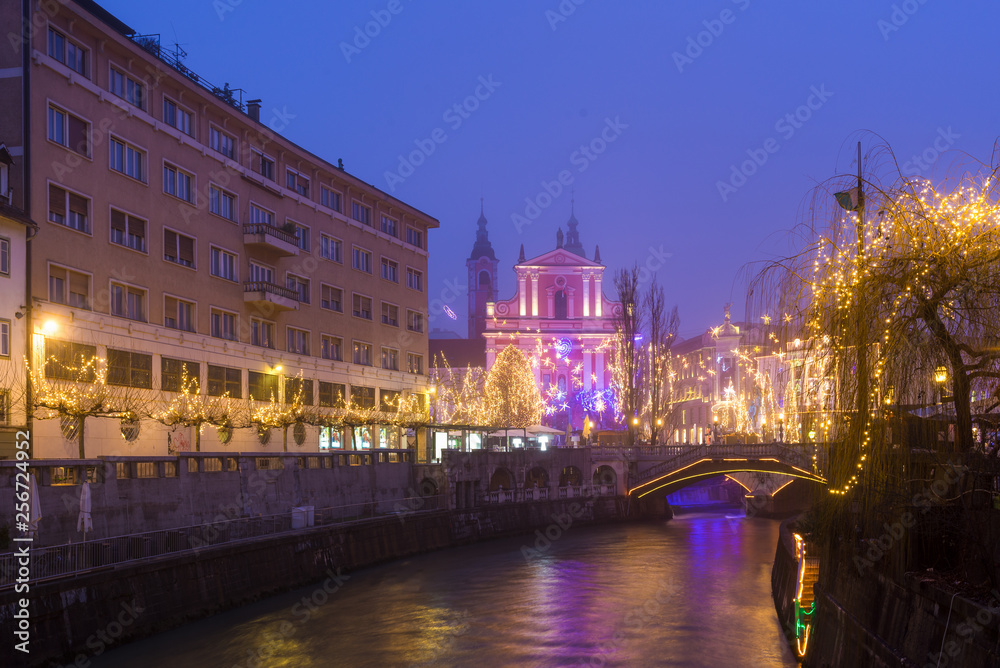 Christmas lights in Ljubljana. Franciscan Church of the Annunciation and Ljubljanica river flowing under the Triple bridge.
