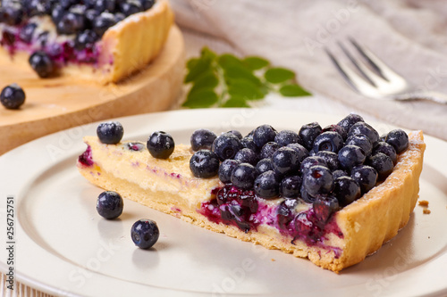 Piece of  custard tart with blueberries on dish