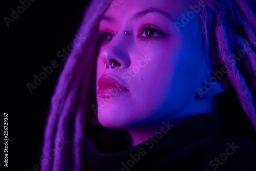 beautiful girl in the light of neon colored lamps light blue purple on black background