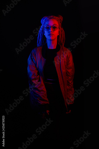beautiful girl in the light of neon colored lamps light on black background blue red wearing glasses