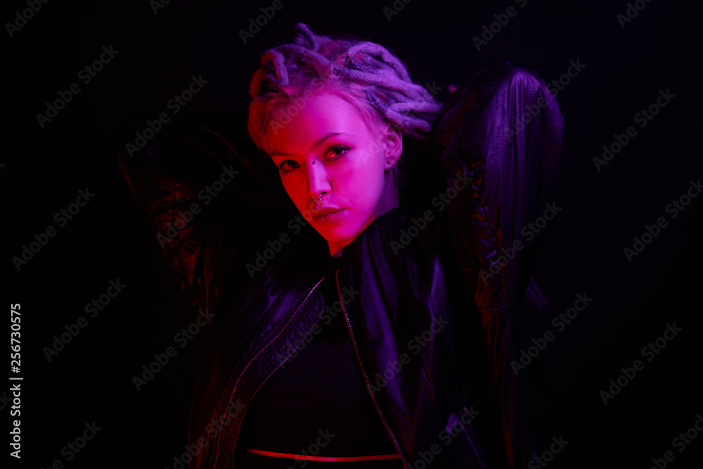 beautiful girl in the light of neon colored lamps light purple red on black background