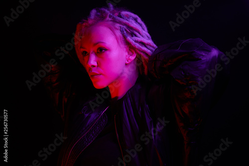 beautiful girl in the light of neon colored lamps light purple red on black background