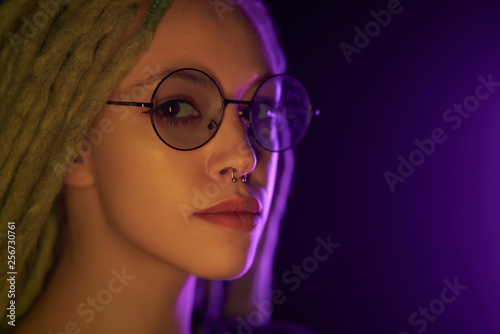Obraz na płótnie beautiful girl in the light of neon colored lamps light yellow purple spectacled