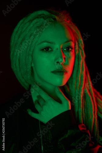 beautiful girl in the light of neon colored lamps light green red on black background