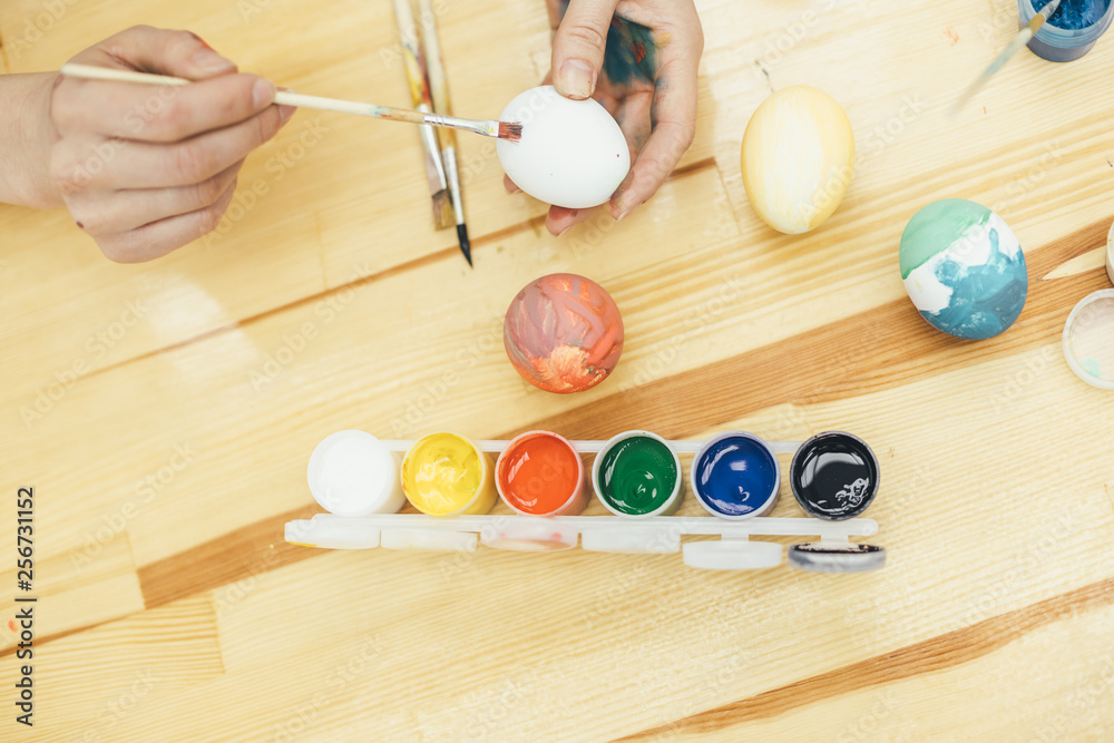 Cropped hands of happy family making various designs on eggs during Easter. Hands are spotted in paint. Cropped hands of happy family making various designs on eggs during Easter. Hands are spotted in paint.