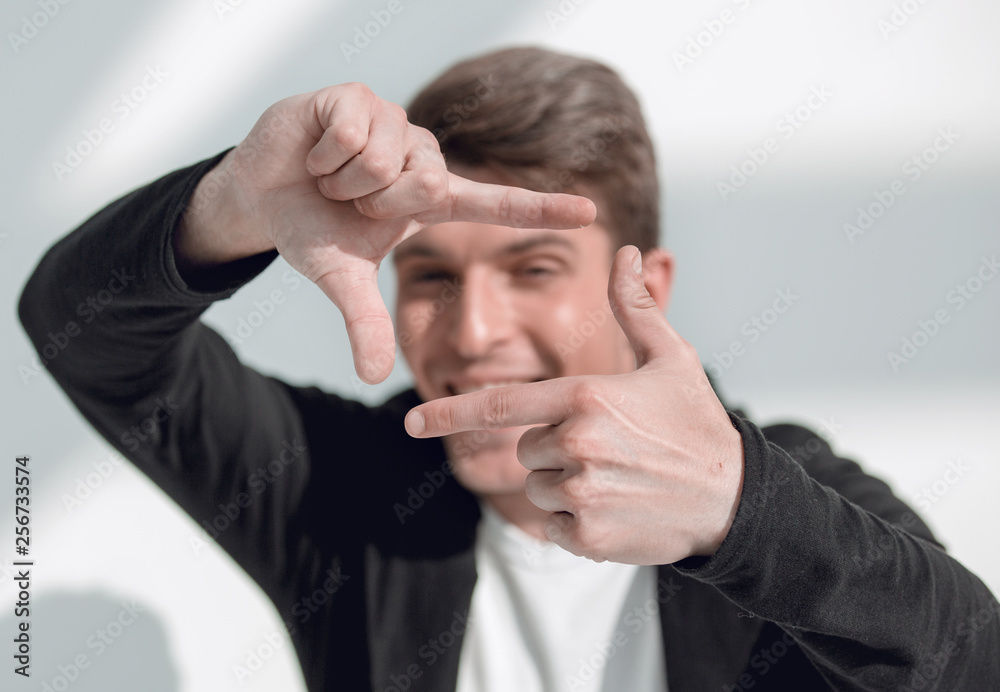 modern guy looks into the frame formed by his hands. modern guy looks into the frame formed by his hands.
