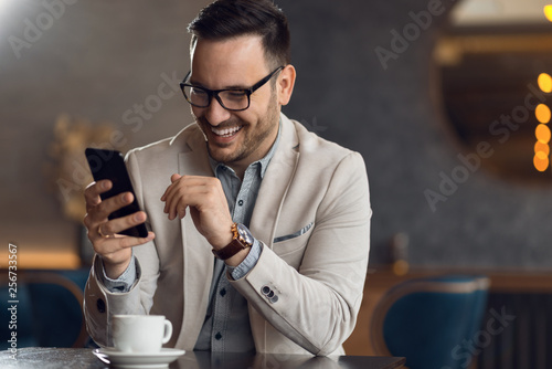 Happy businessman reading a text message on smart phone.